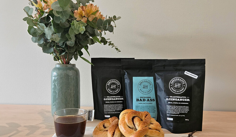 Røverkaffe og kanelbolle på bord med blomster